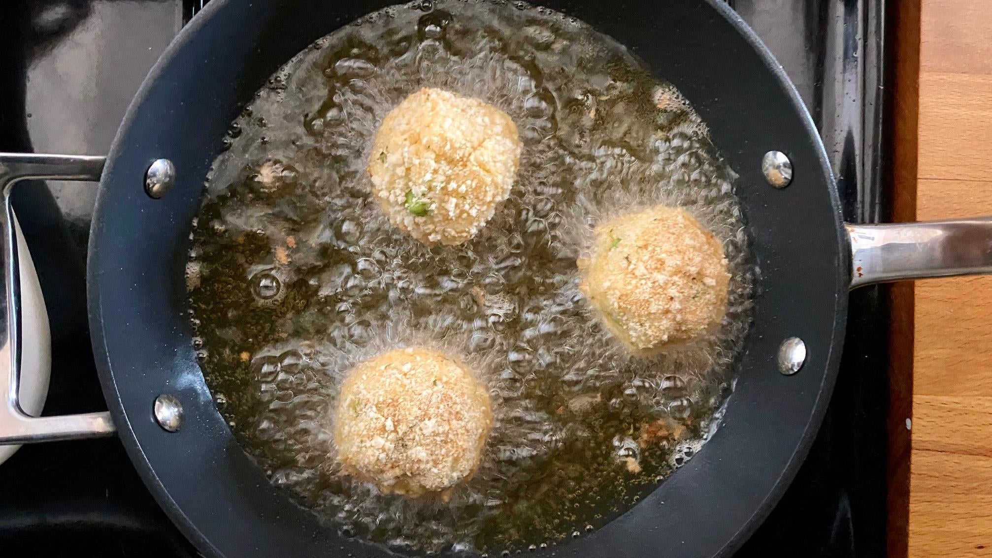 Arancini frying on their first side. (Photo: Allie Chanthorn Reinmann)