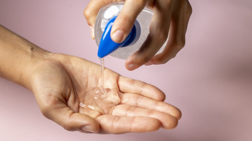 hand sanitiser Cropped woman hands using alcohol-based hand sanitizer on pink background