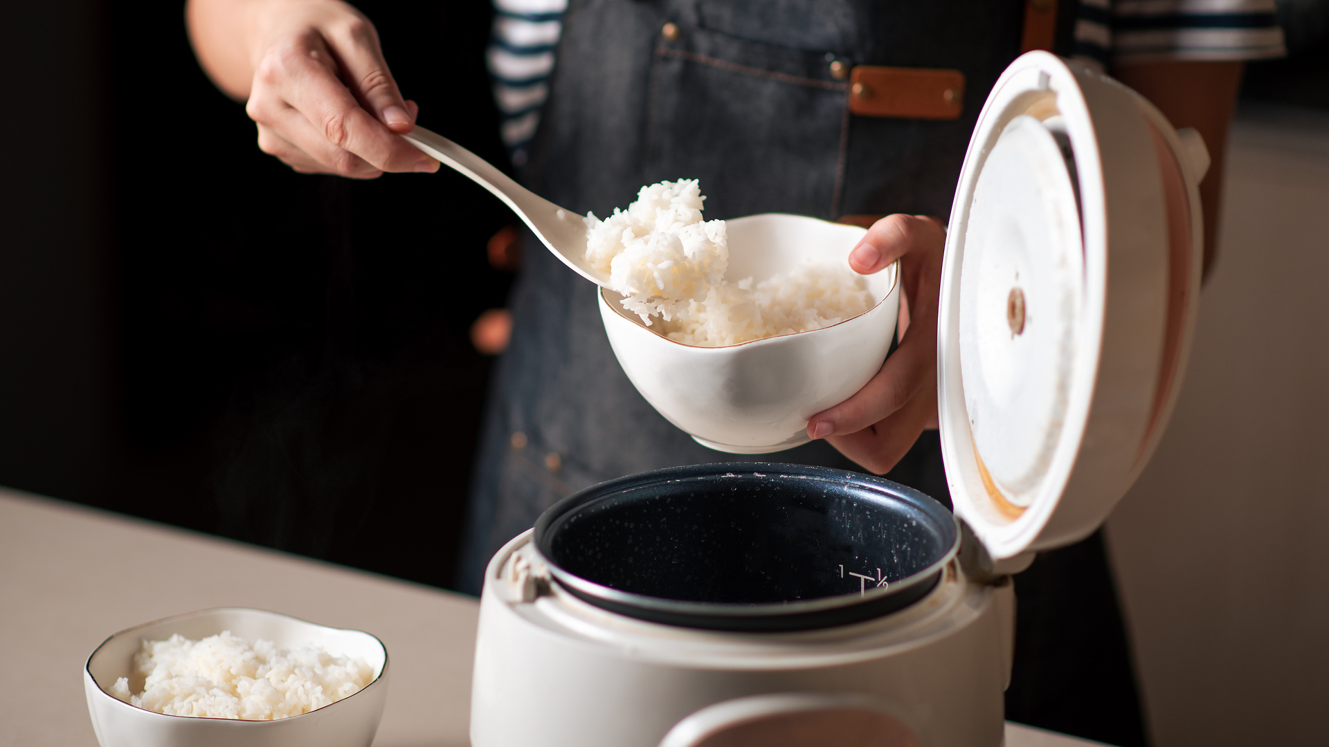 Woman taking out and serving fresh boiled rice from the cooker